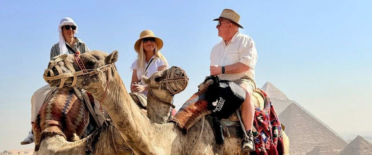 Tre viaggiatori sui cammelli davanti alle Piramidi di Giza