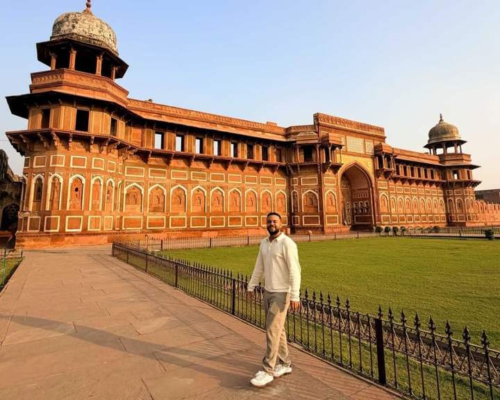 Viaggiatore sul prato davanti al palazzo in arenaria rossa Jahangiri Mahal, al Forte di Agra, India