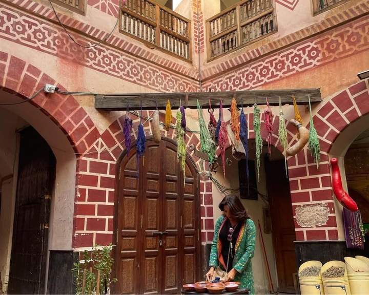 Viaggiatrice che prepara spezie nel cortile di un riad addobbato con lana tinta a Marrakech