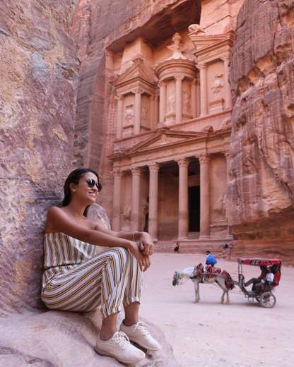 Viaggiatrice seduta sulle rocce davanti al Tesoro di Petra, Giordania