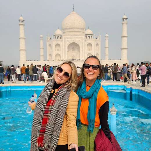 Due amiche con sciarpe sorridono davanti al Taj Mahal, India