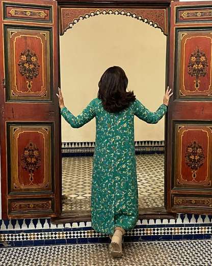 Viaggiatrice che apre porte di legno dipinto su un cortile piastrellato a Marrakech